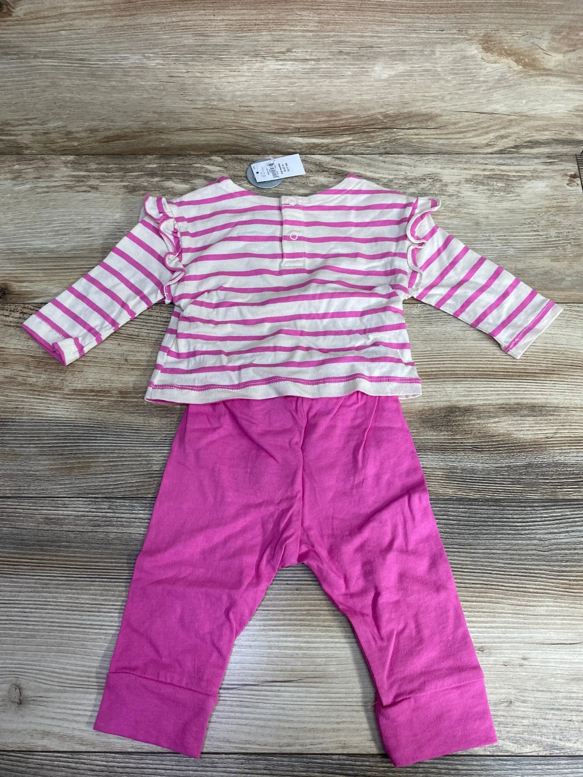 Baby girl outfit with pink and white striped top featuring ruffles and solid pink pants on wooden floor