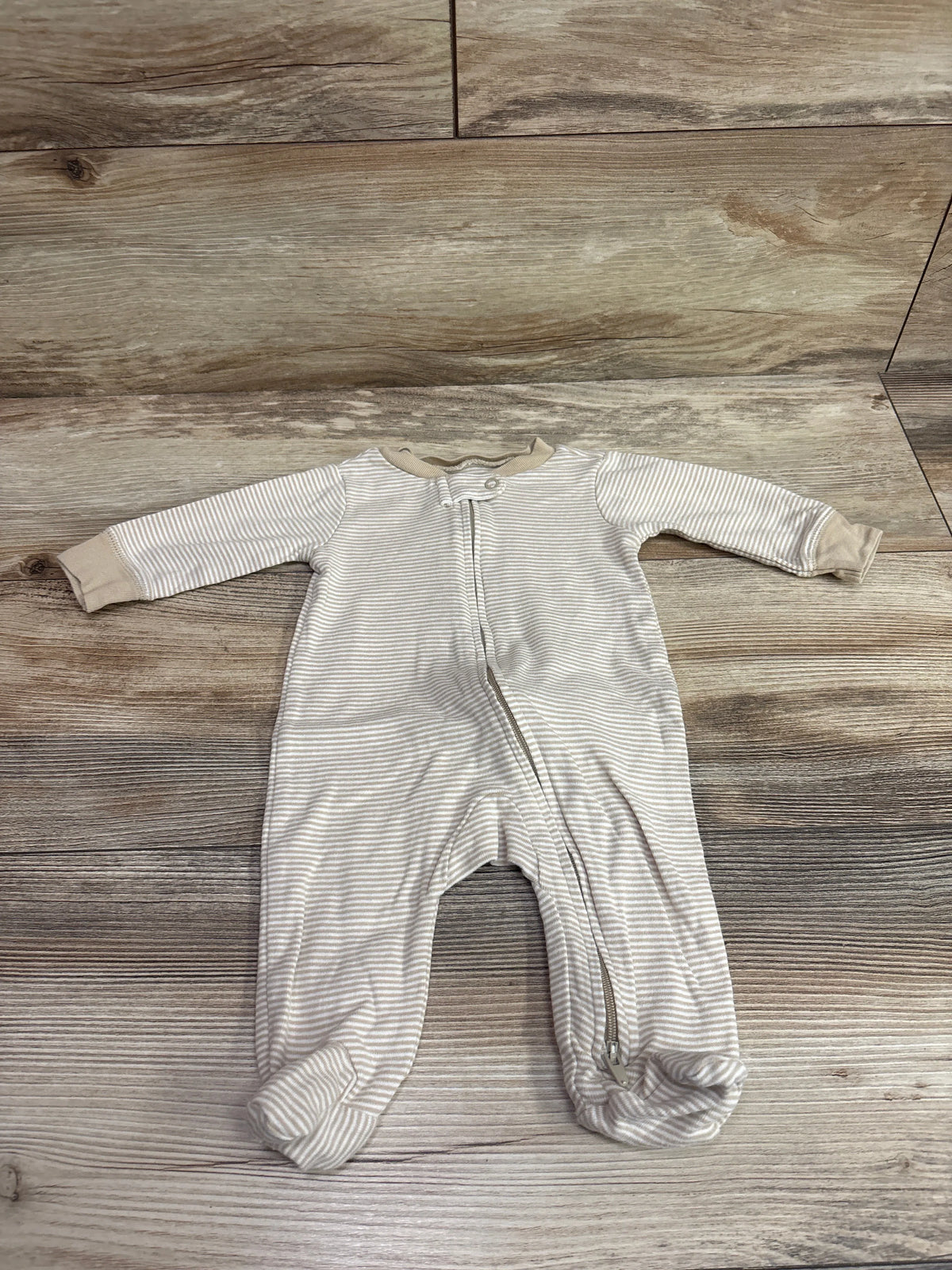 Beige striped Carter's baby sleeper with zipper, size 3m, on a wood-grain background
