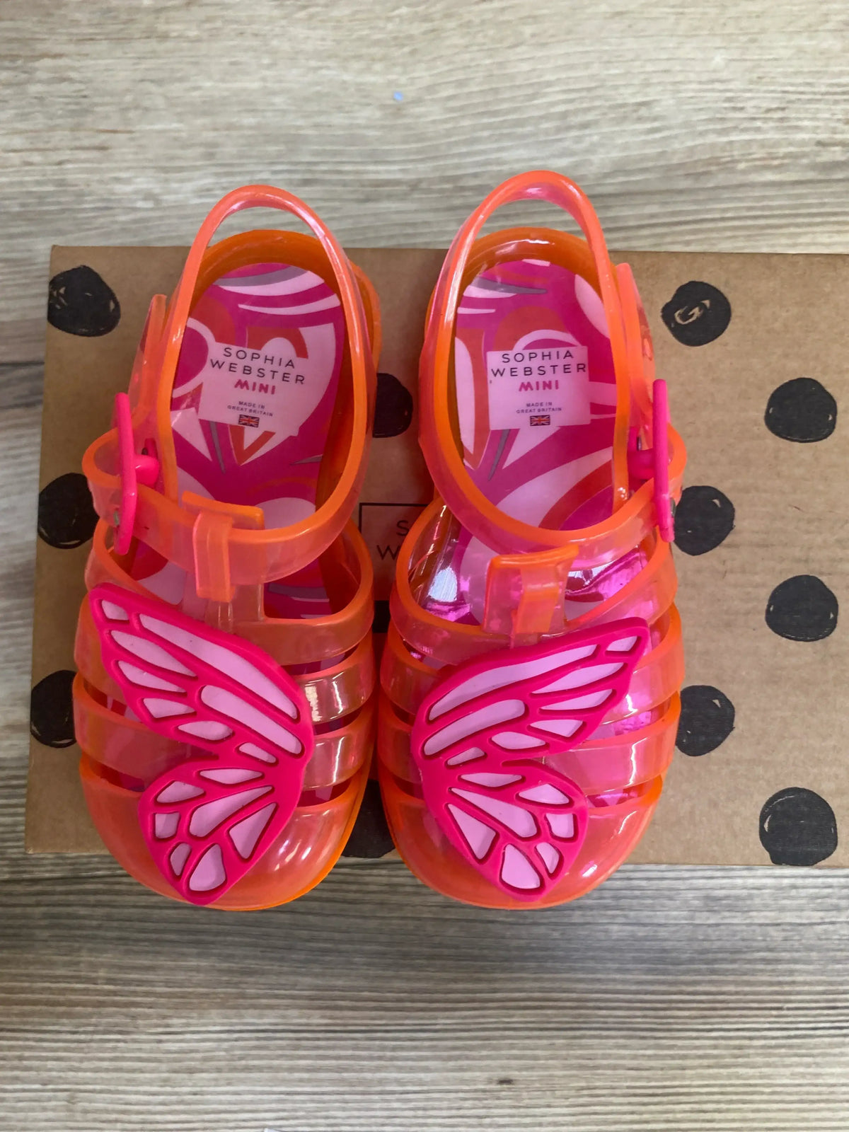 Front view of Sophia Webster toddler pink jelly sandals featuring butterfly wings on a white background