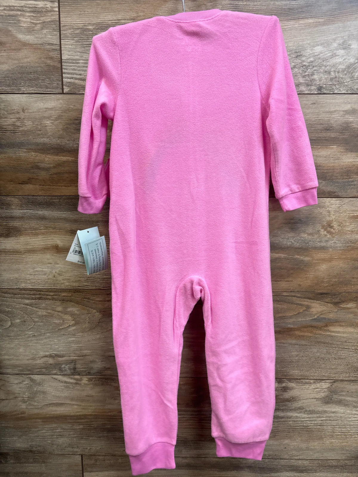 Flat lay of pink Care Bears sleeper from a two-piece hat and sleeper set, with long sleeves and ribbed cuffs on wood flooring
