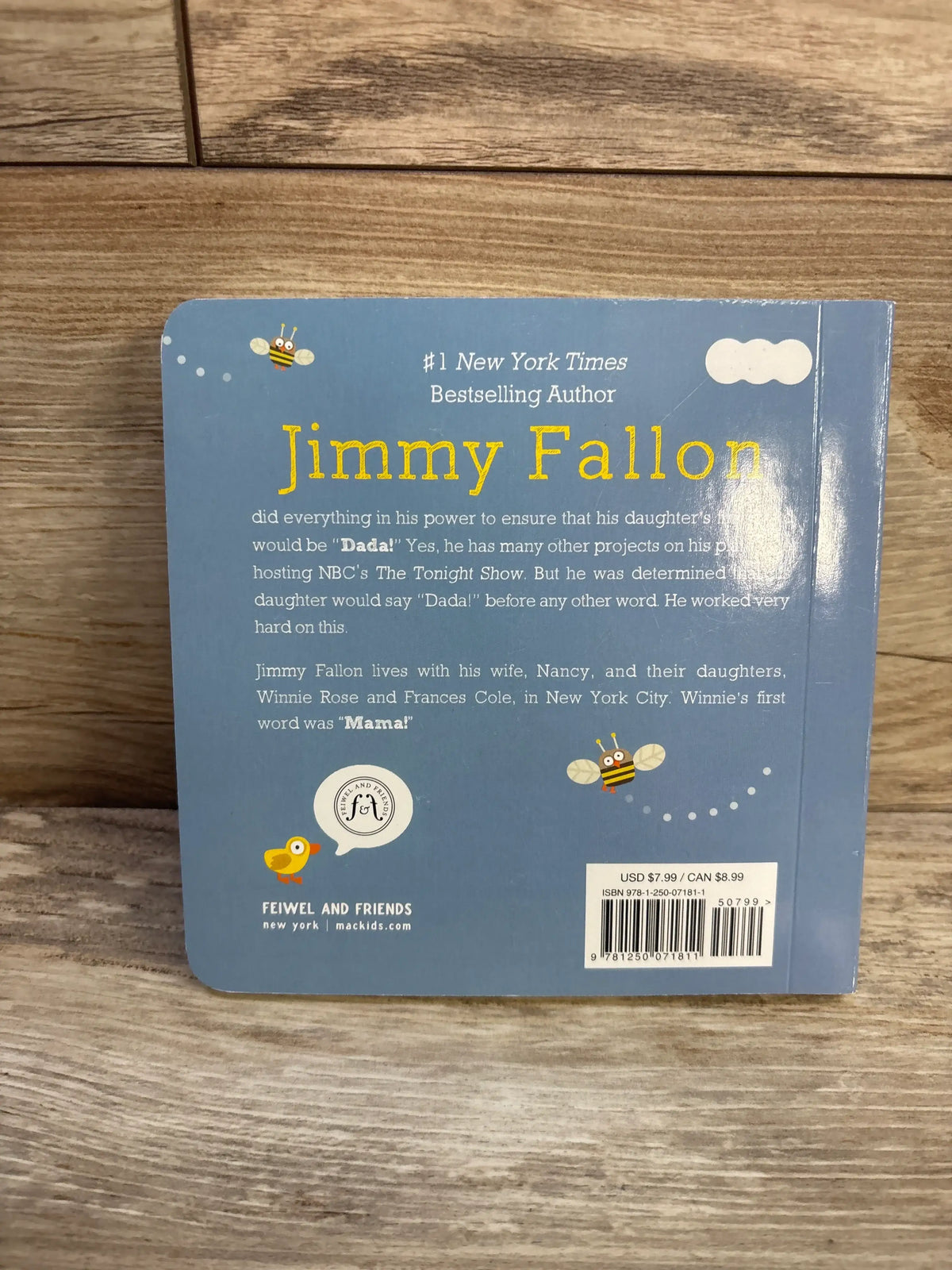 Back cover of Your Baby’s First Word Will Be Dada board book with Jimmy Fallon bio and bee illustrations on blue