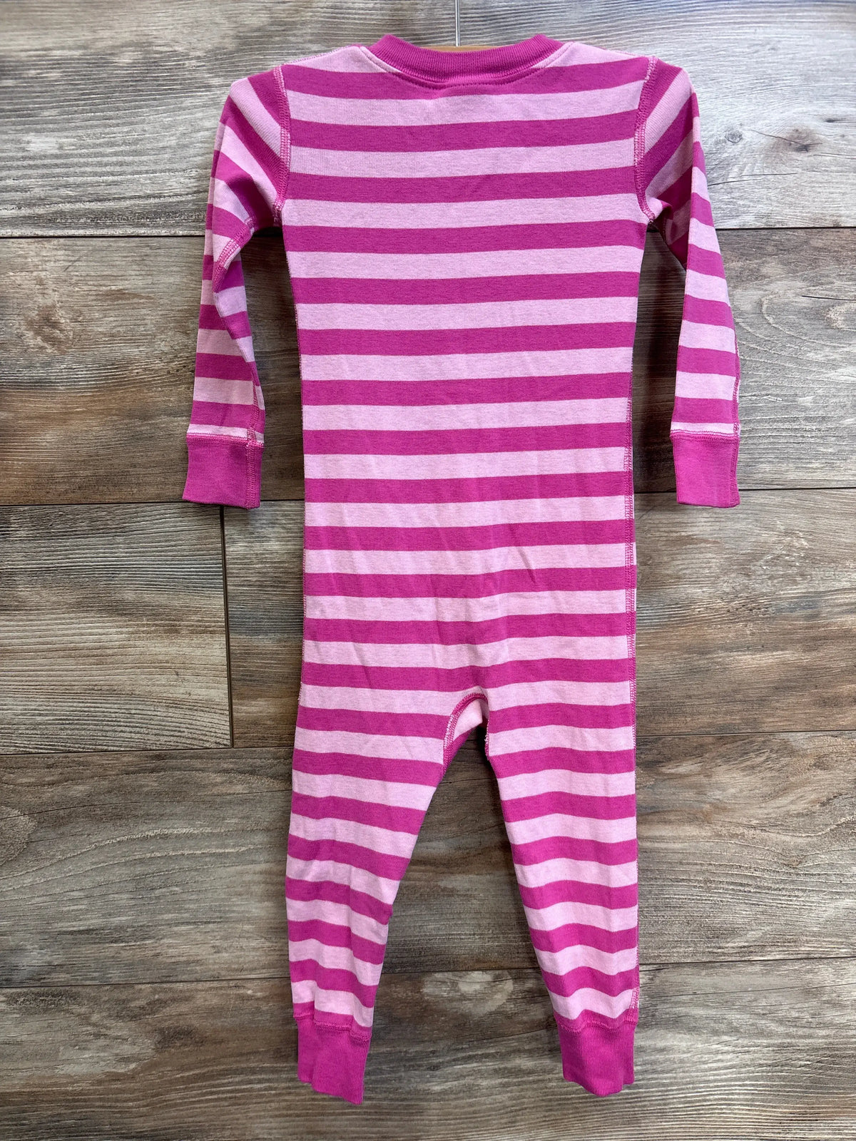 Front view of Hanna Andersson pink striped footless sleeper in size 3T, showcasing long sleeves and cuffed legs on wood