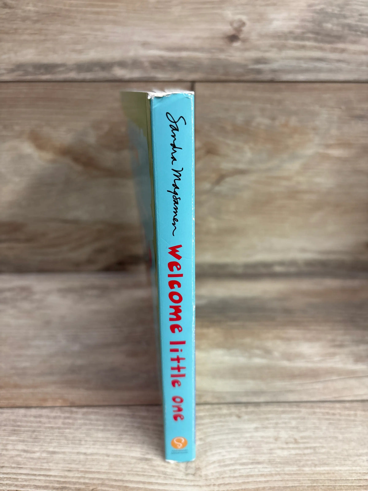 Spine of Welcome Little One board book by Sandra Boynton on a wooden surface.