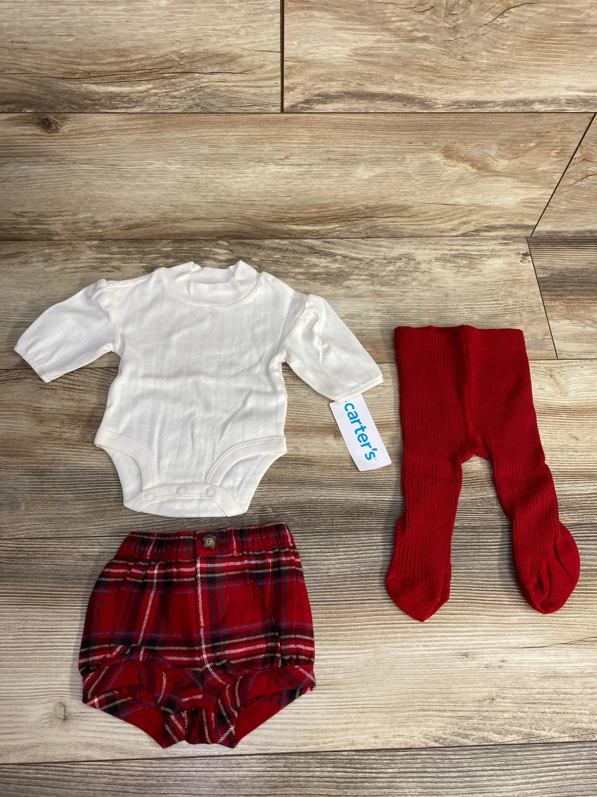 Carter's baby outfit with white bodysuit, red plaid shorts, and red ribbed tights on wood floor