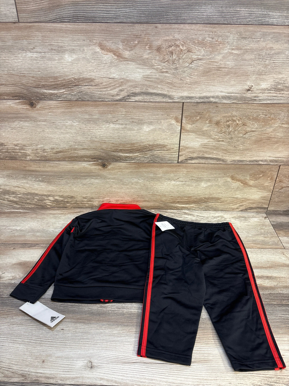 Black and red toddler tracksuit set with pants and jacket on wooden floor