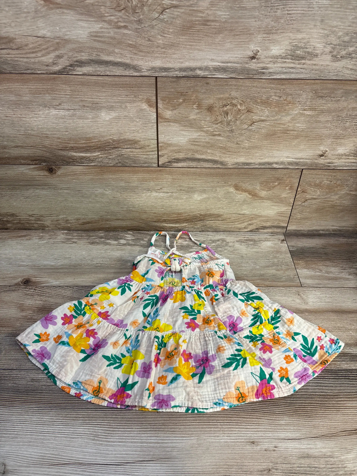 Front view of Cat & Jack ivory gauze tank dress showcasing colorful floral print and tank straps on a wood floor