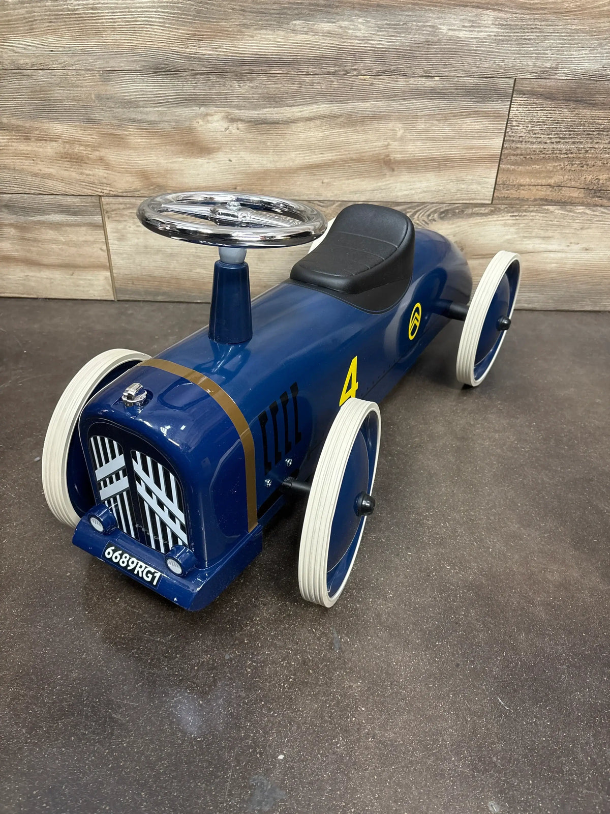 Blue vintage-style metal ride-on toy car with white wheels, black seat, and silver steering wheel