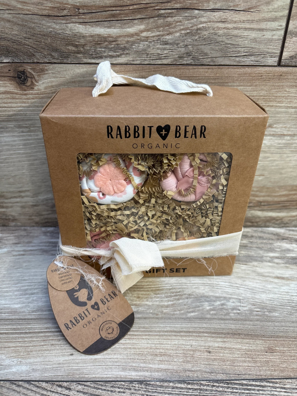 Rabbit Bear Organic baby gift set with pink booties in kraft box on wood background