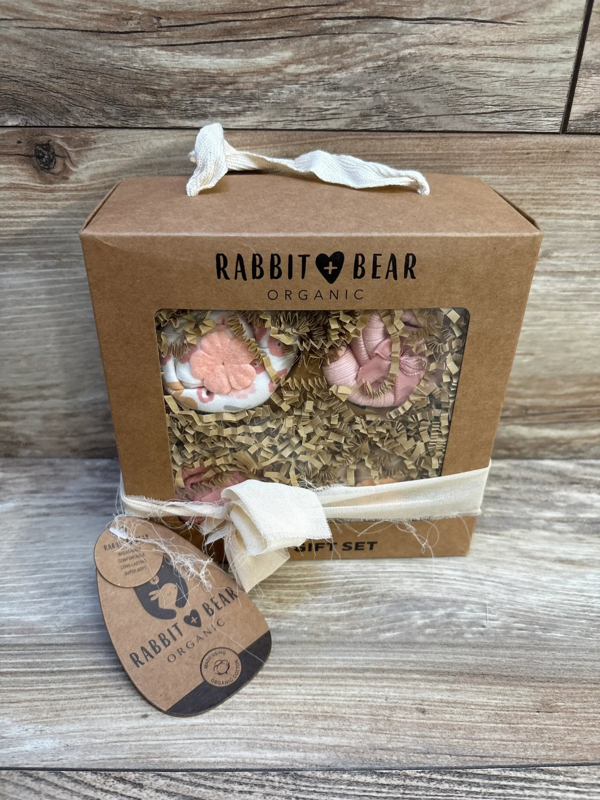 Rabbit Bear Organic baby gift set with pink booties in kraft box on wood background