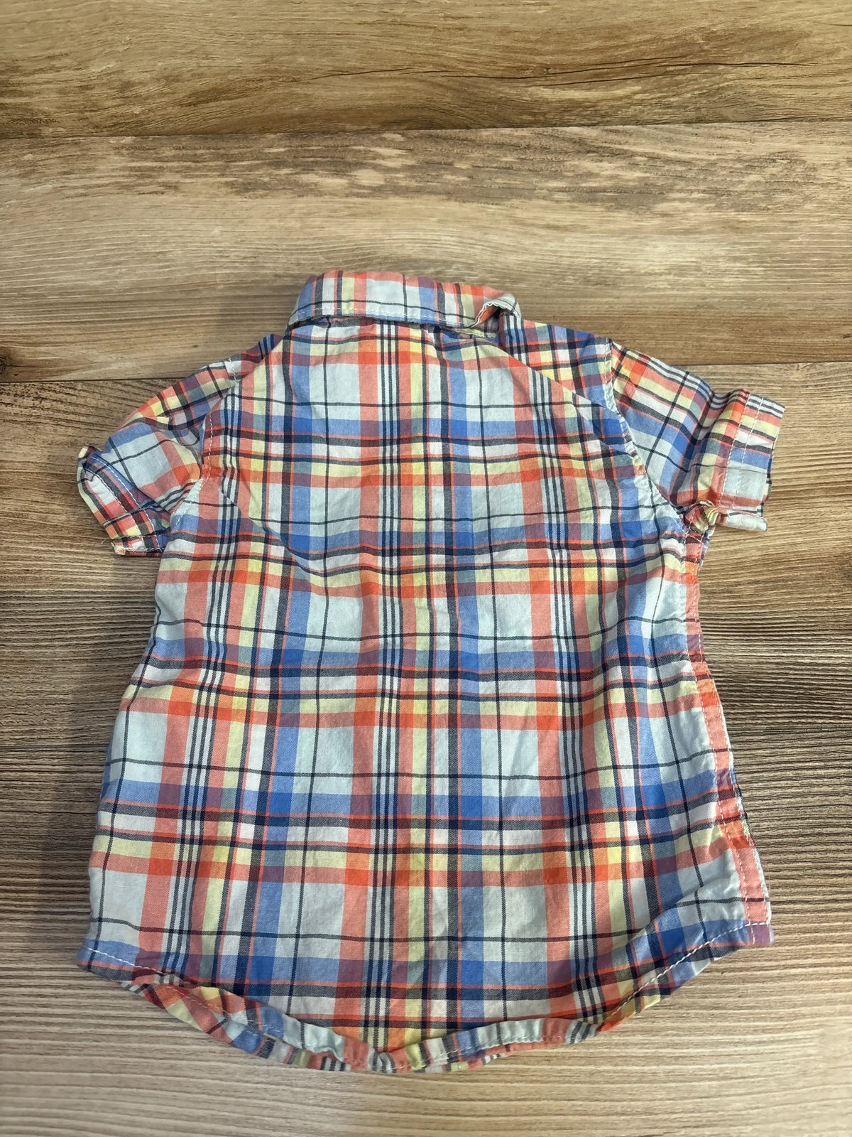 Back view of Carter’s blue plaid short-sleeve baby button-up shirt with rolled sleeves on wood background
