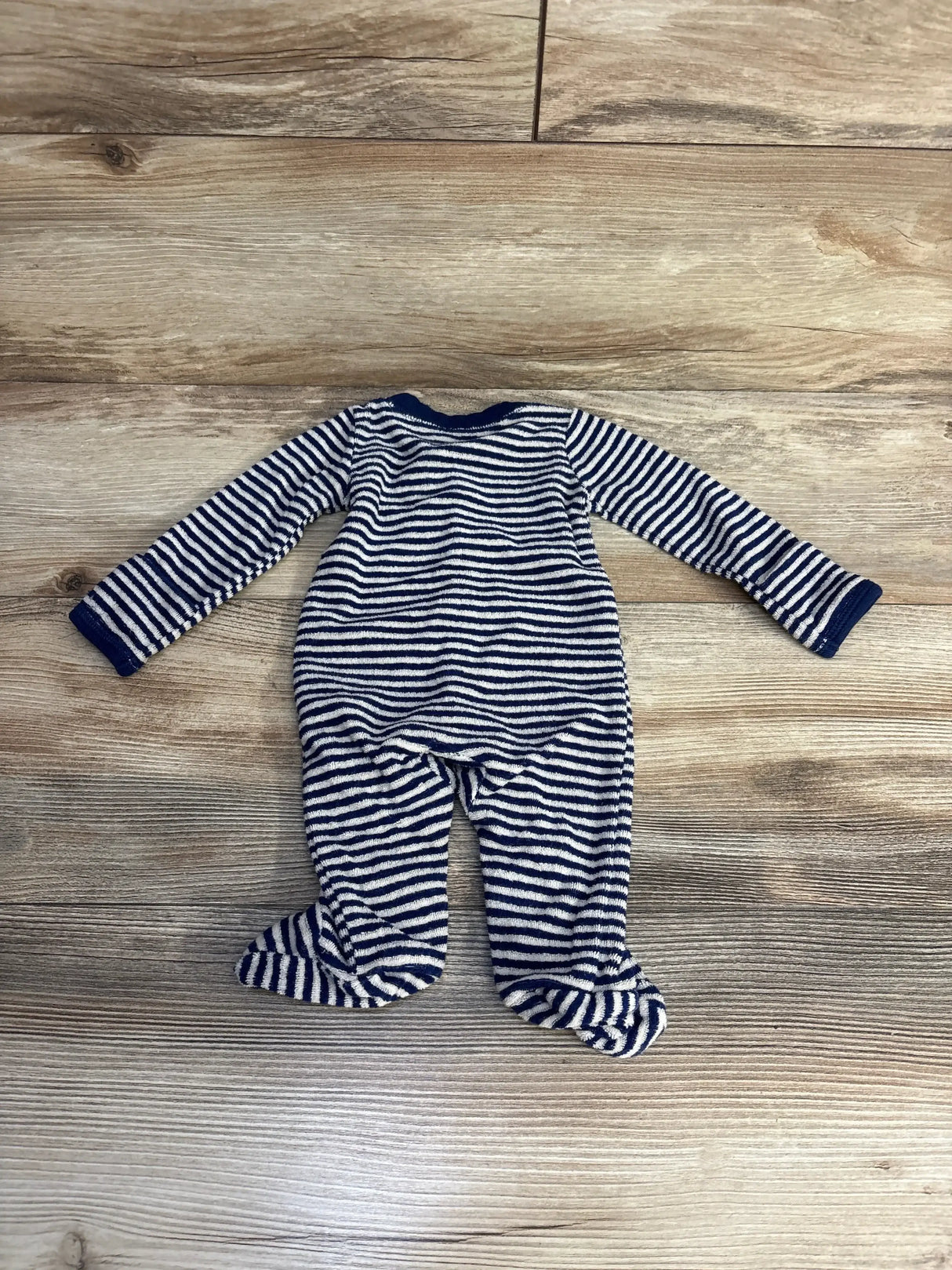 Flat lay of Carter’s newborn terry footed sleeper, navy-striped, long-sleeve with enclosed feet on wood background
