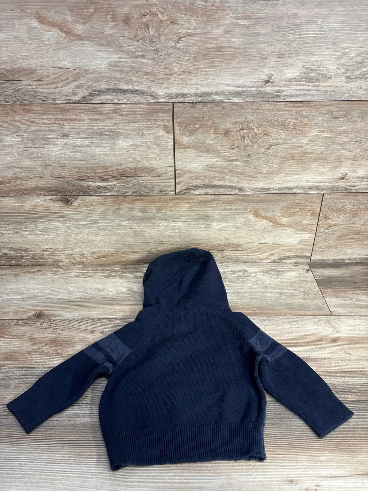 Navy blue toddler hoodie with striped sleeves on wood background