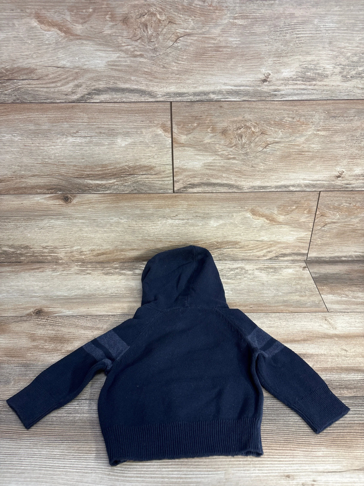 Navy blue toddler hoodie with striped sleeves on wood background