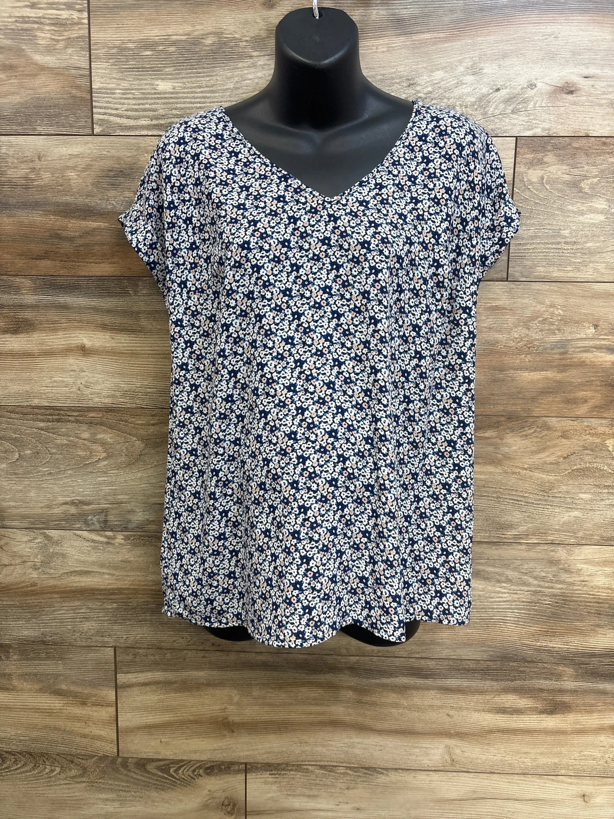 Front view of Motherhood Maternity blue floral V-neck shirt showcasing relaxed fit on a black mannequin against wood backdrop