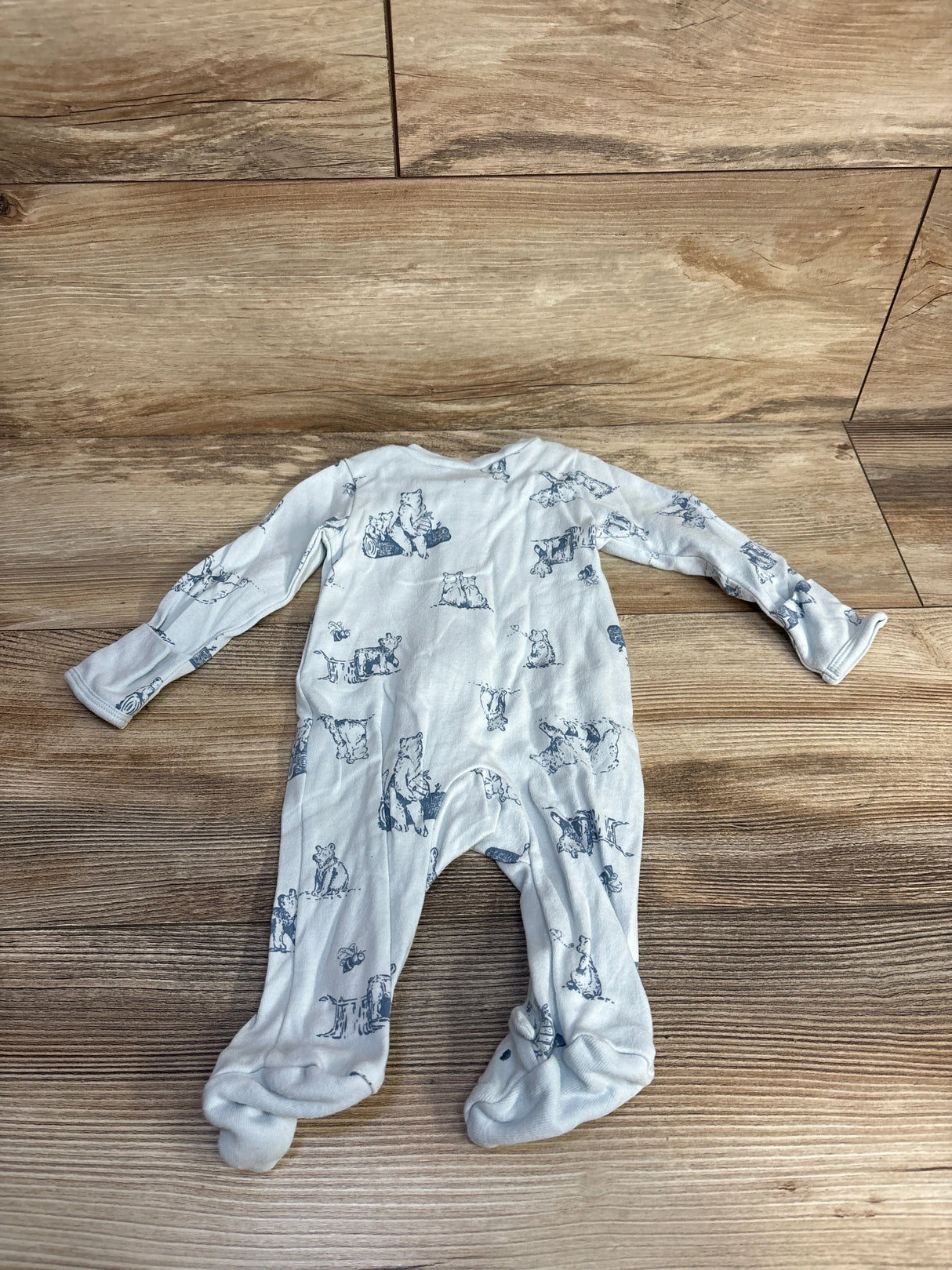 White baby sleeper with animal print on wooden floor