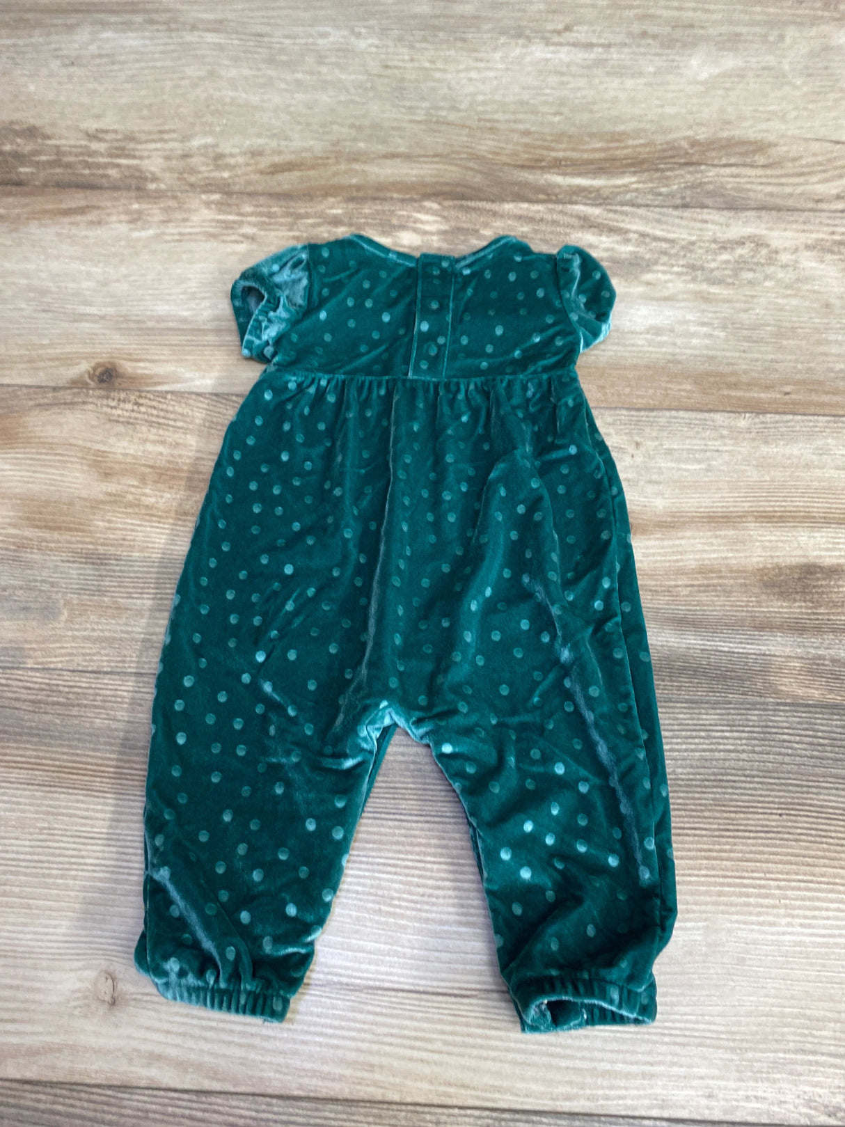 Green velvet baby romper with polka dots on wooden floor for kids clothes resale