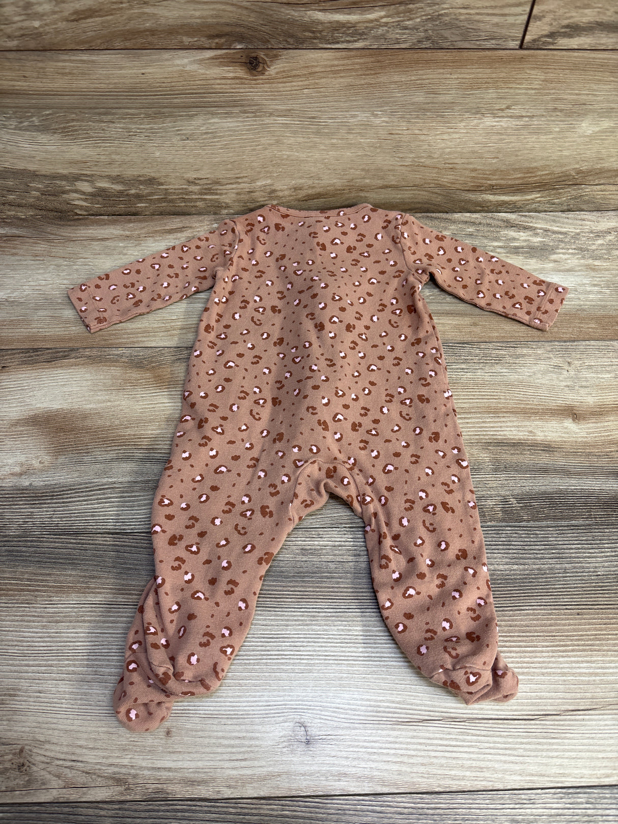 Brown leopard print baby sleeper on wooden floor, long sleeves and footed design