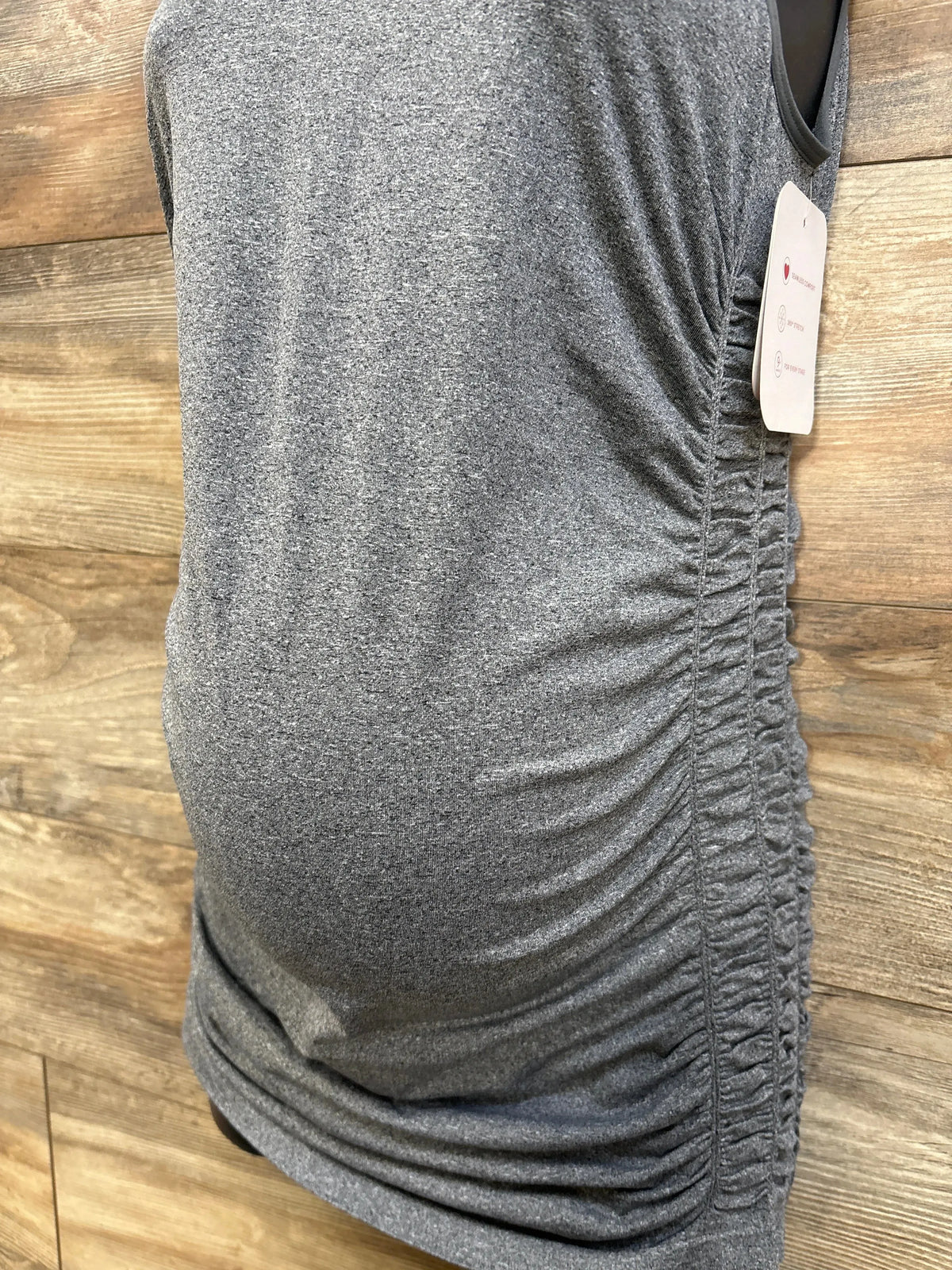Side view of Isabel ruched maternity tank top in heather gray showcasing side ruching and fitted tummy shaping against a wood background