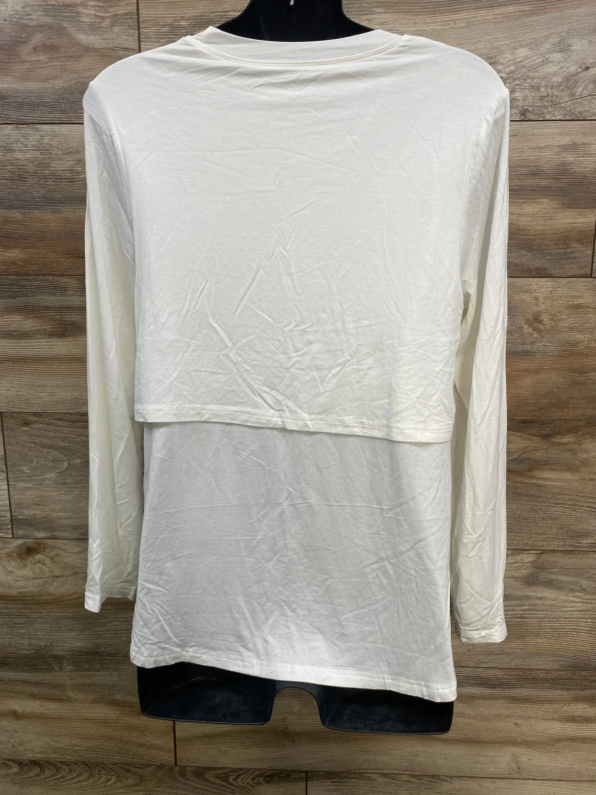 White long-sleeve layered shirt displayed on mannequin against wooden background