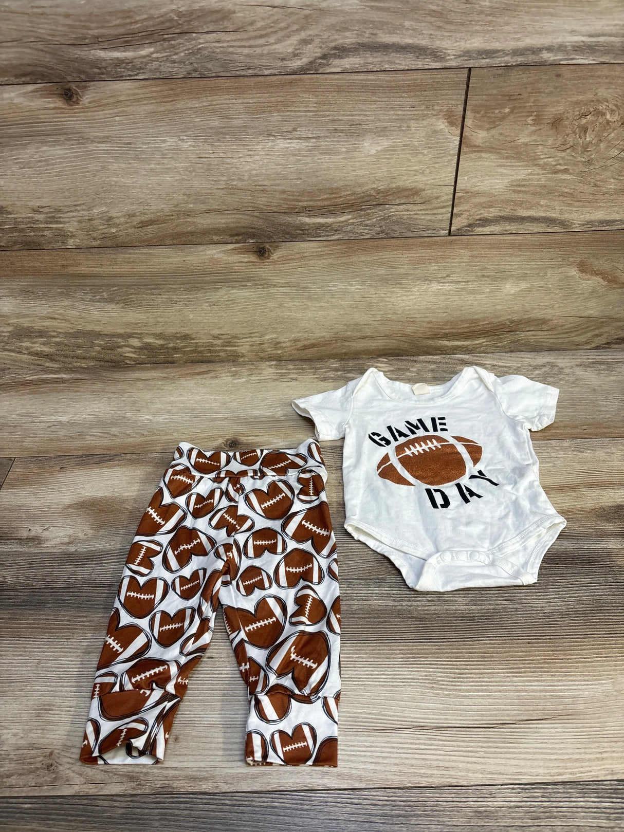 Baby football outfit with pants and white Game Day onesie on wood floor