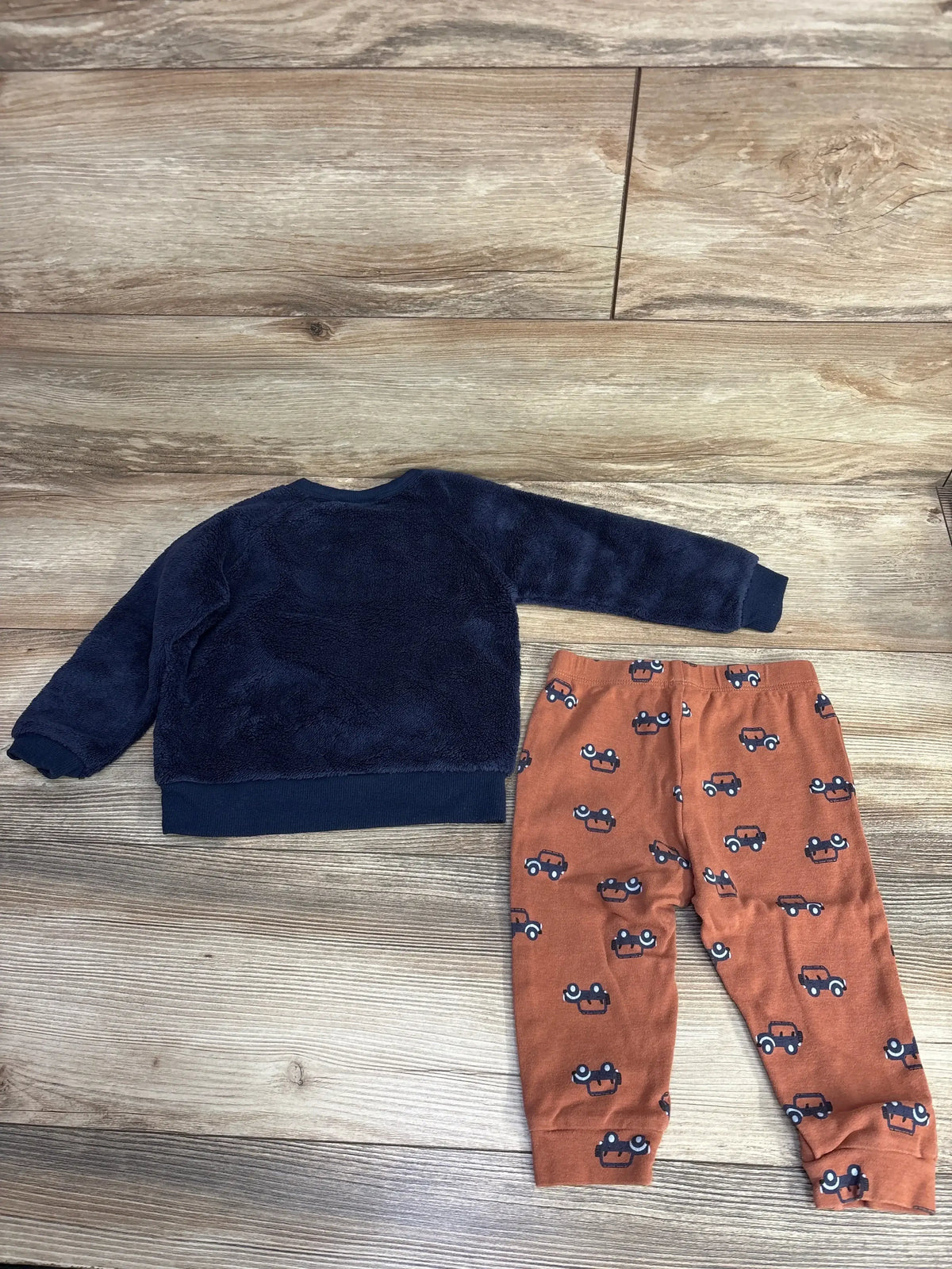 Children's outfit with navy blue fuzzy long-sleeve top and rust-colored pants featuring small car prints
