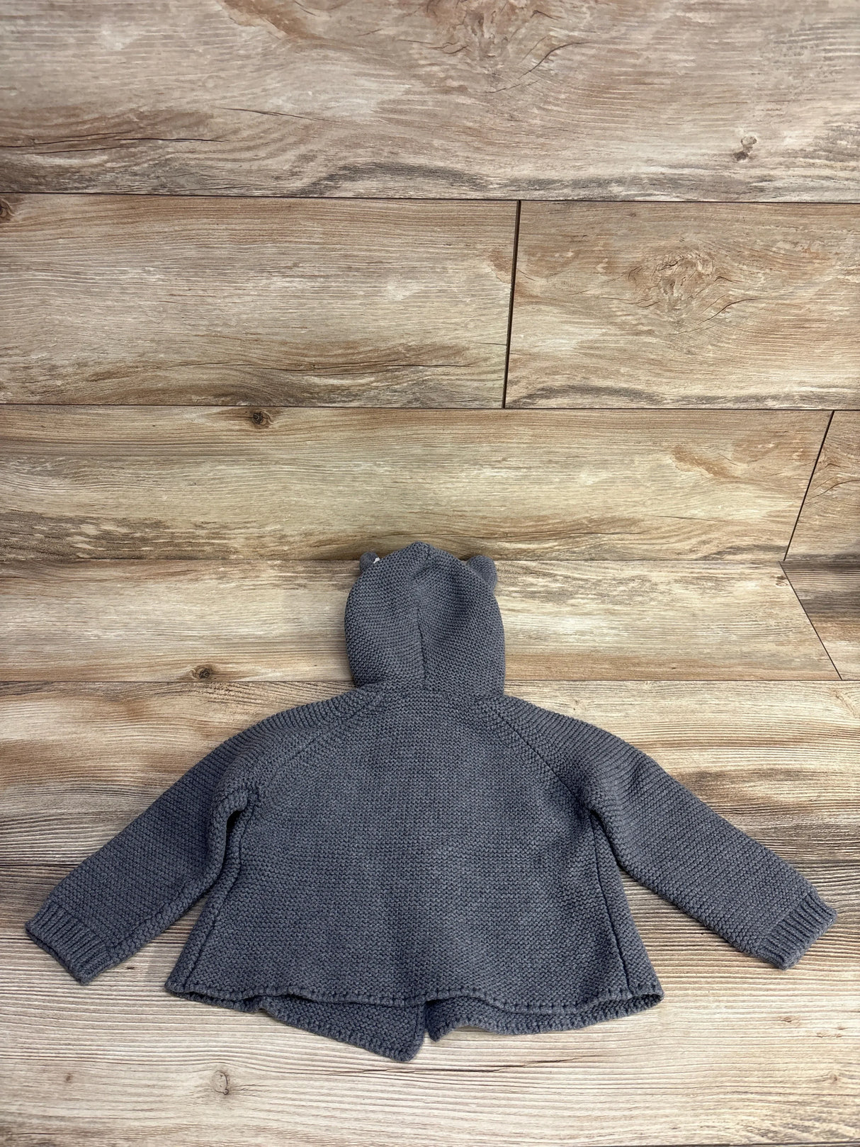 Back view of grey knitted bunny ear cardigan 9m showing hood with ears and textured knit on wooden background