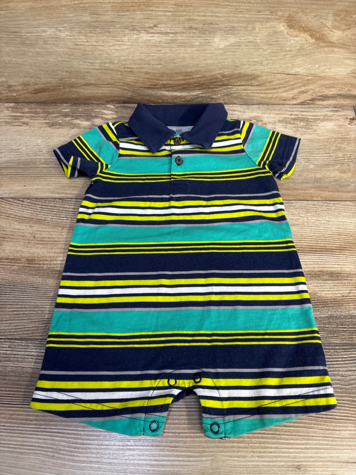 Front view of navy Simple Joys striped polo shortie romper showcasing polo collar and short legs on wood background
