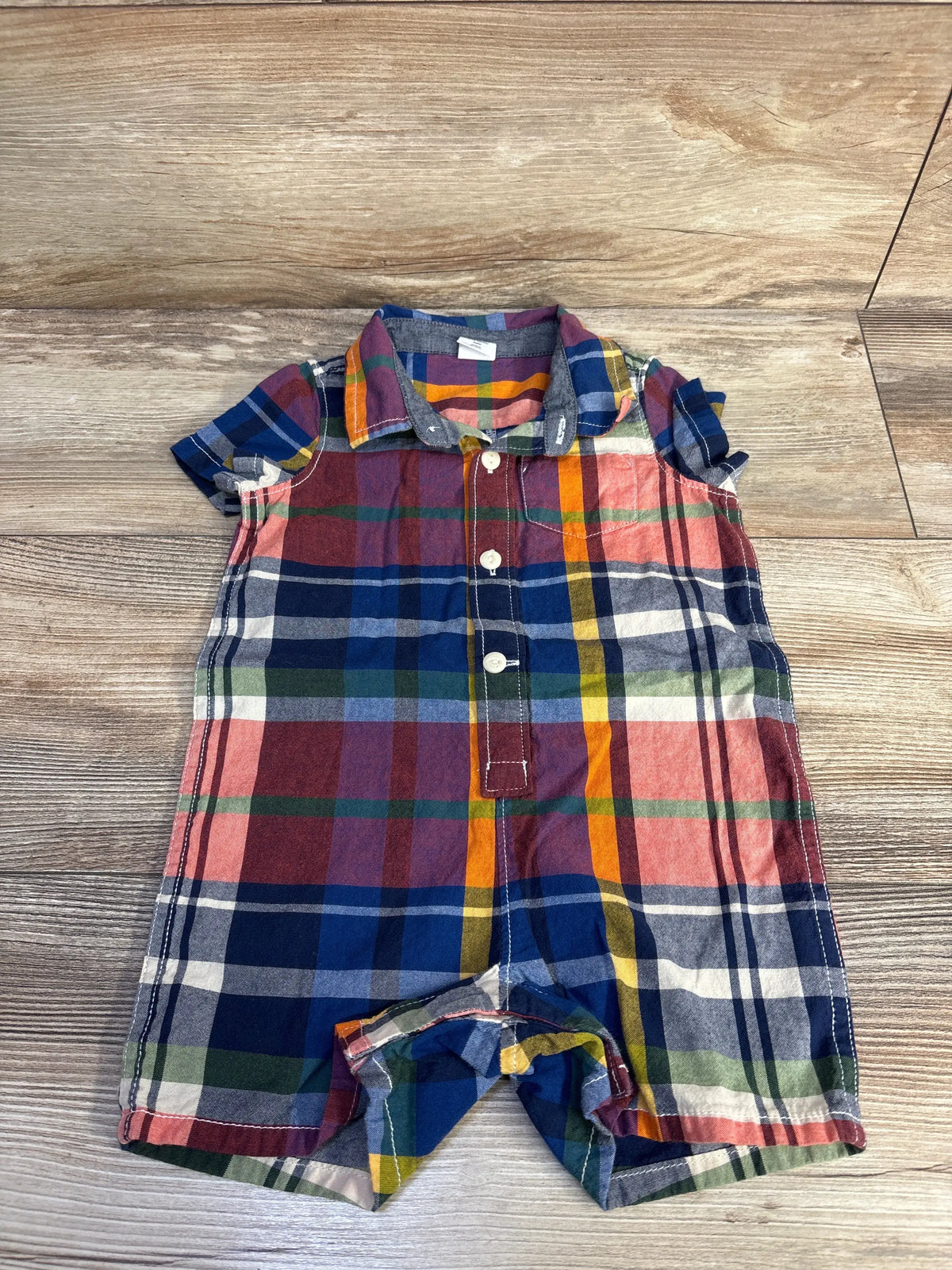 Front view of Baby Gap blue plaid polo romper showcasing polo collar and button front on a wood floor