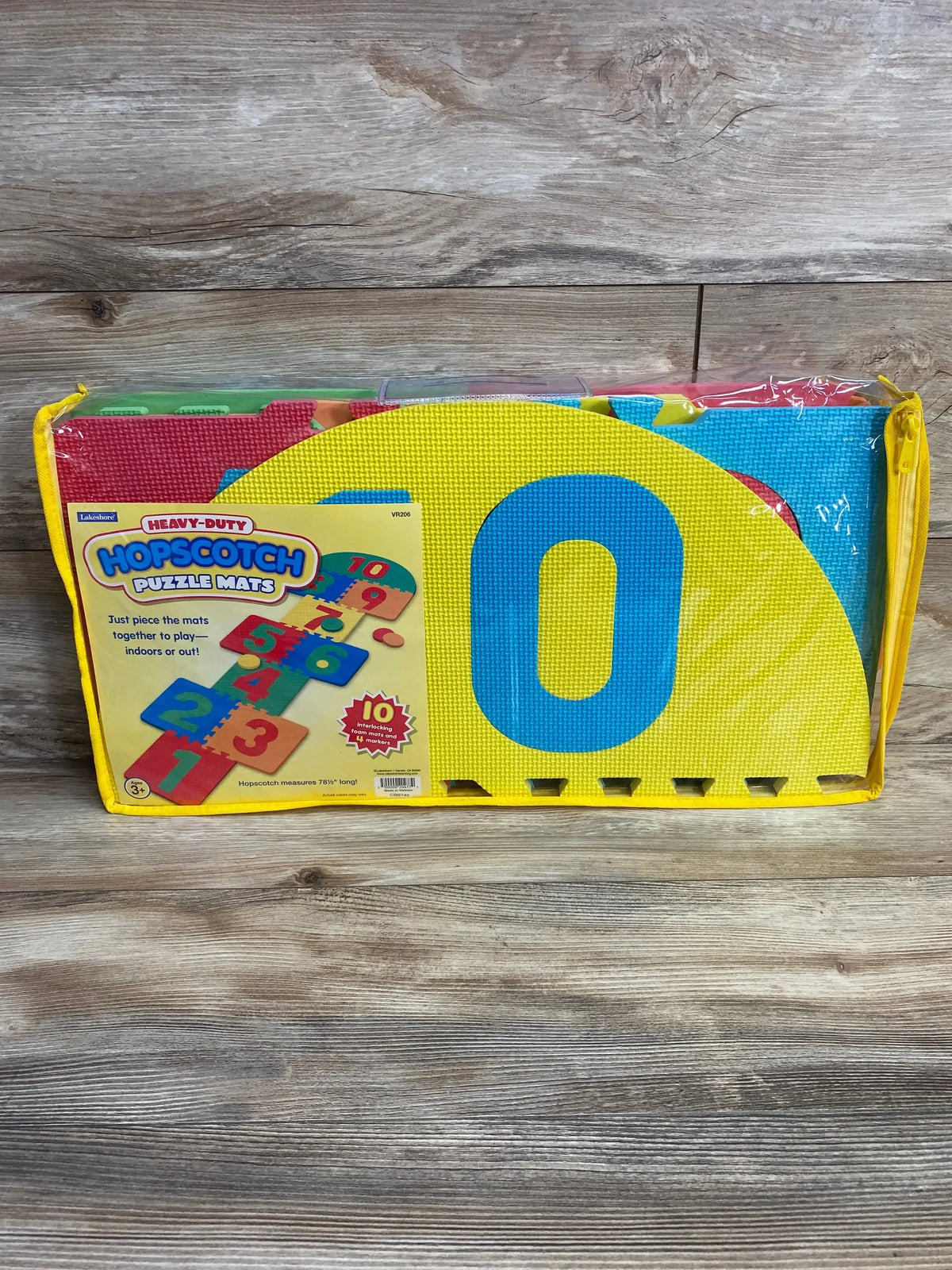 Front view of Lakeshore hopscotch foam puzzle mats in clear yellow-trim carry case showing large yellow 0 and numbered pieces