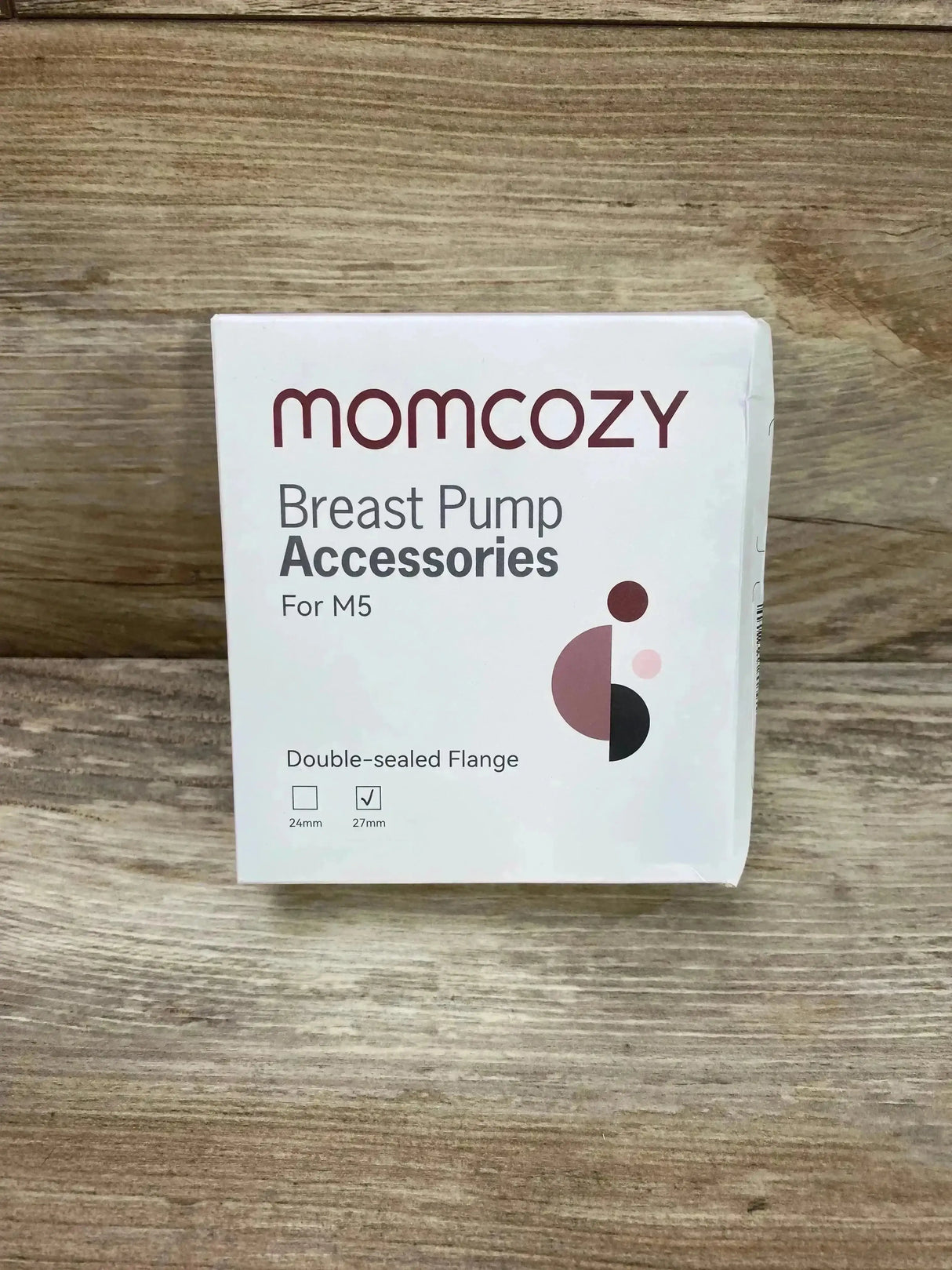 Front view of Momcozy flange packaging showcasing checked 27mm size and Breast Pump Accessories text on wooden background