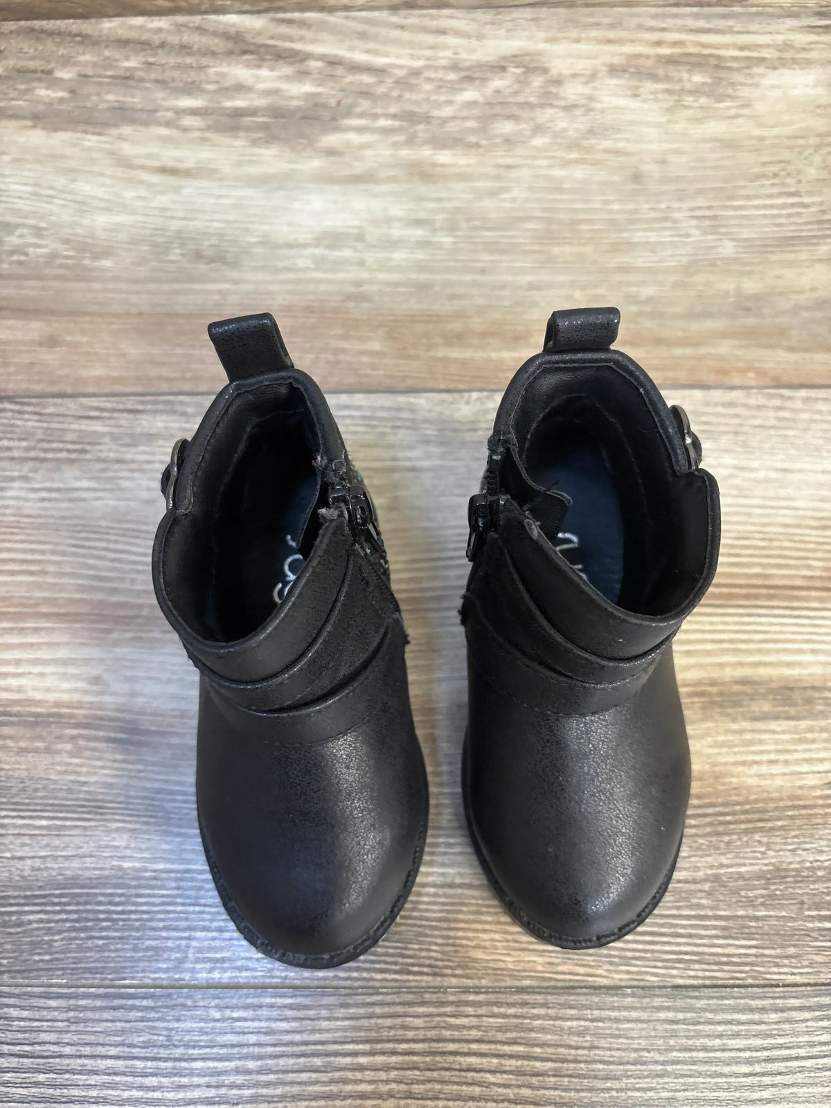 Black toddler boots with side zippers and pull tabs, kids footwear on wood floor