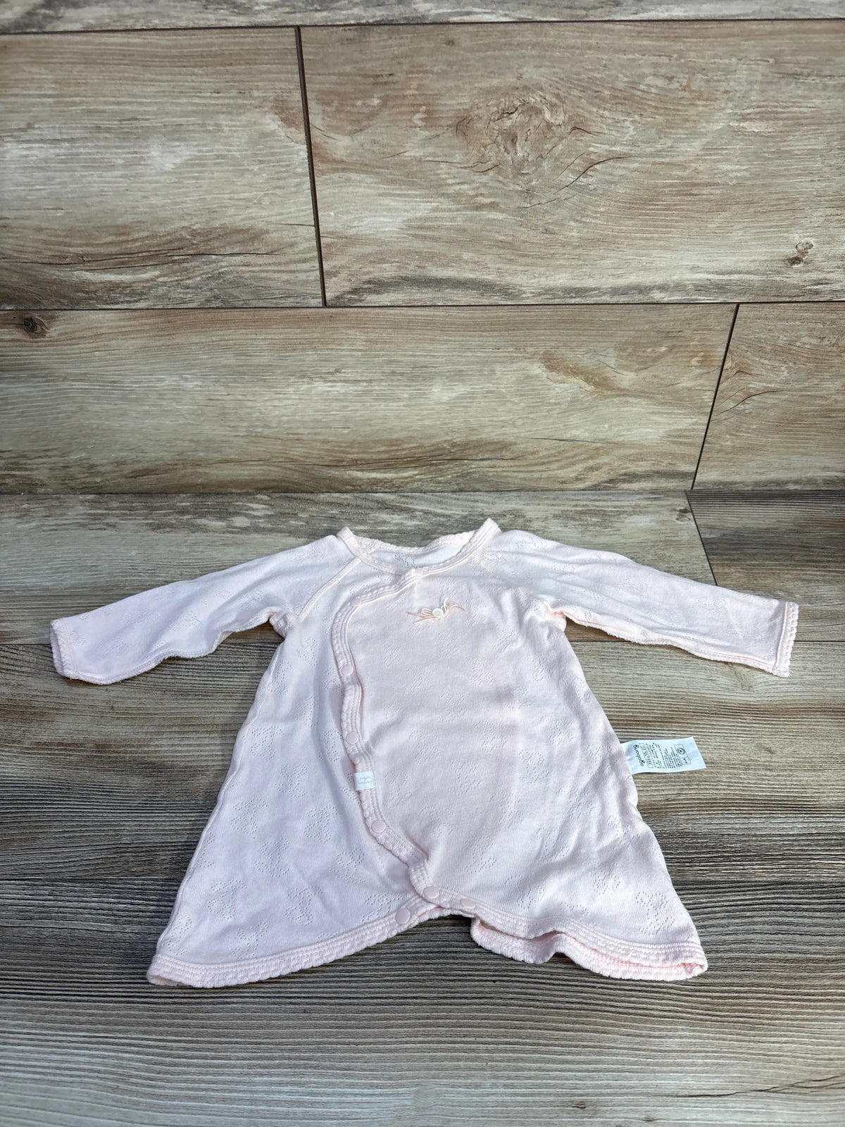 Flat lay of Agabang pointelle knit kimono romper, newborn 0-3m, pale pink, showing knit texture and side-snap wrap on wood