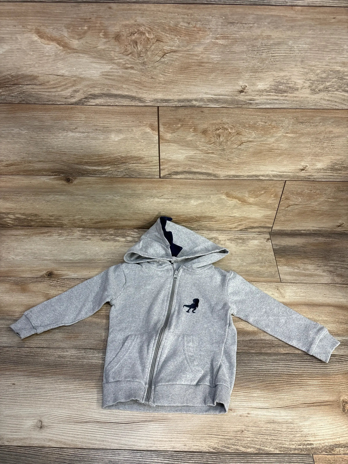 Front view of Copper Denim zip-up sweatshirt in grey, size 2T, showcasing full zipper, hood and navy dinosaur logo on wooden floor