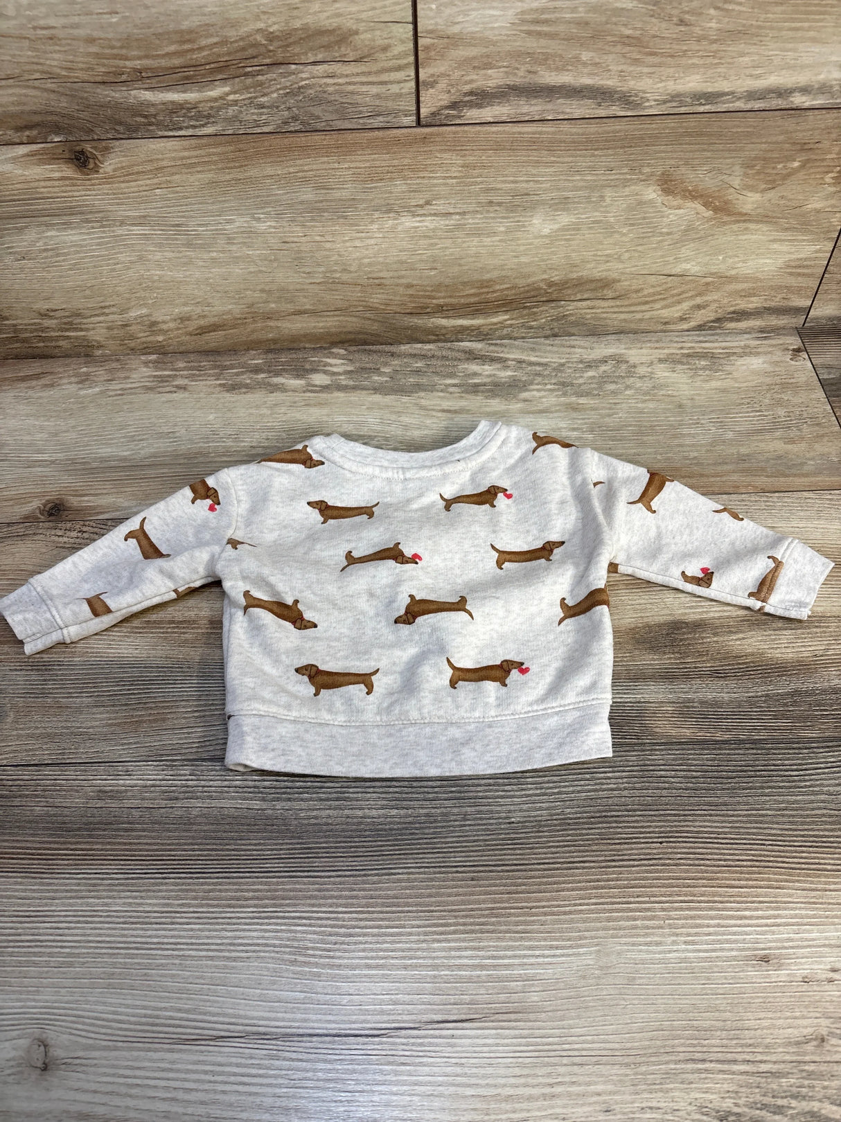 Gray long sleeve baby shirt with brown dog pattern, laid flat on wood background