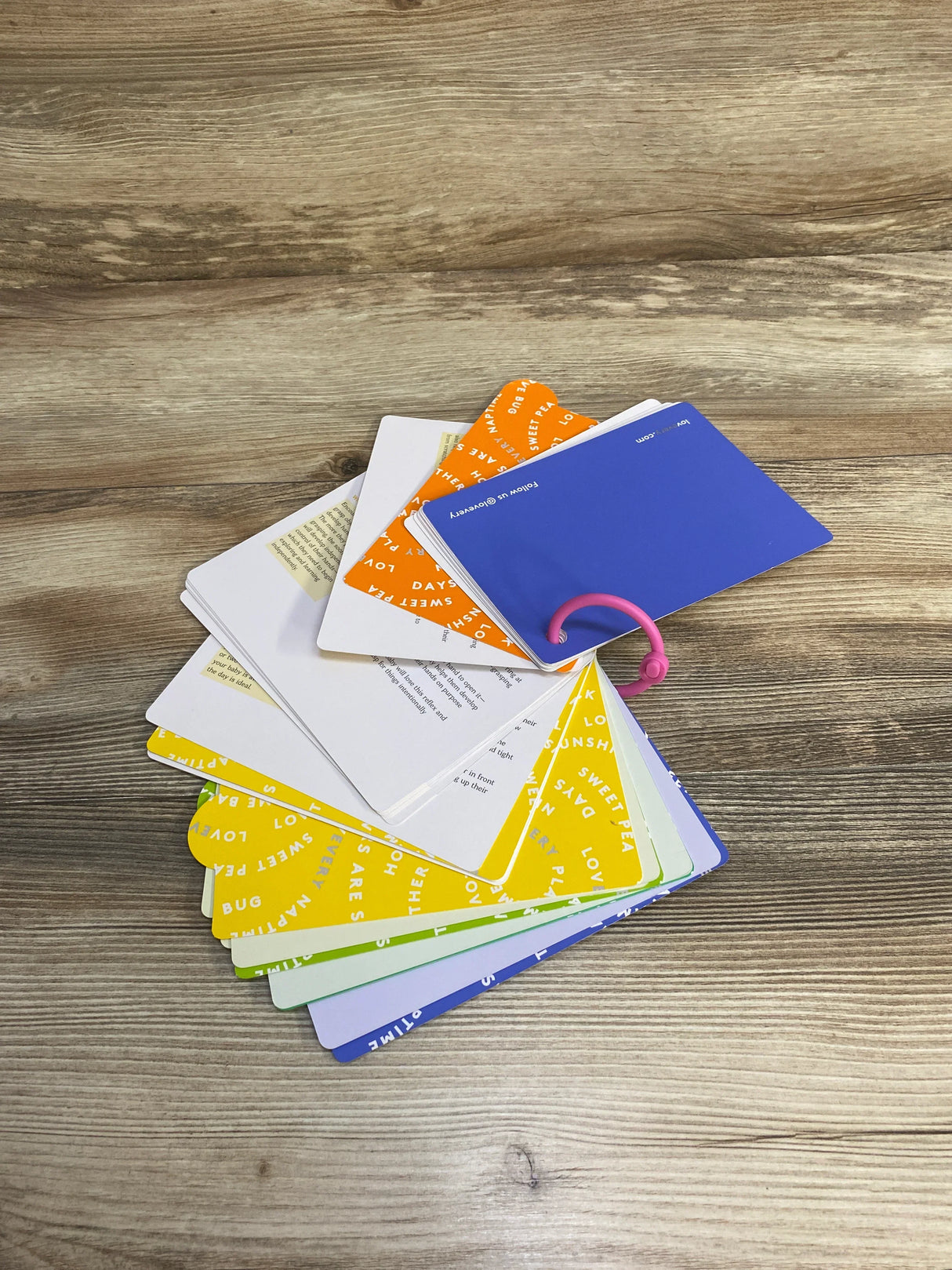 Colorful flashcards with text on a pink ring, displayed on a wooden table