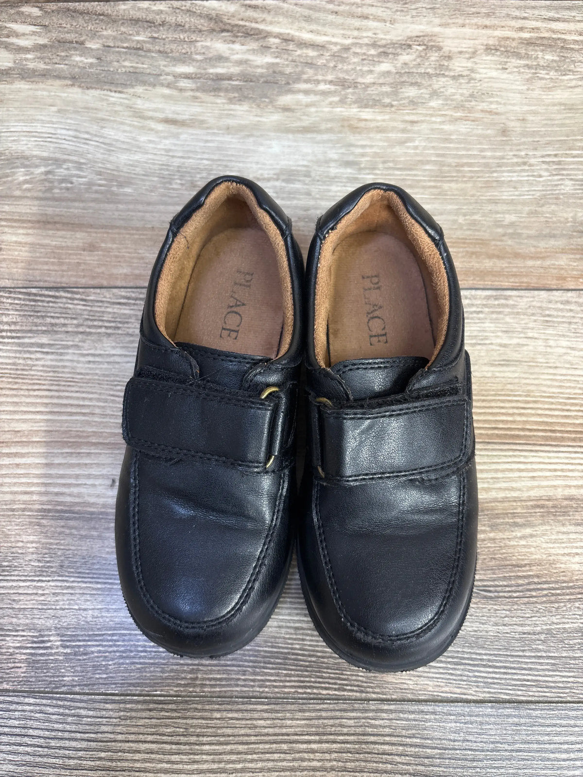 Children's Place black faux leather dress shoes for kids, size 11c, on a wood background