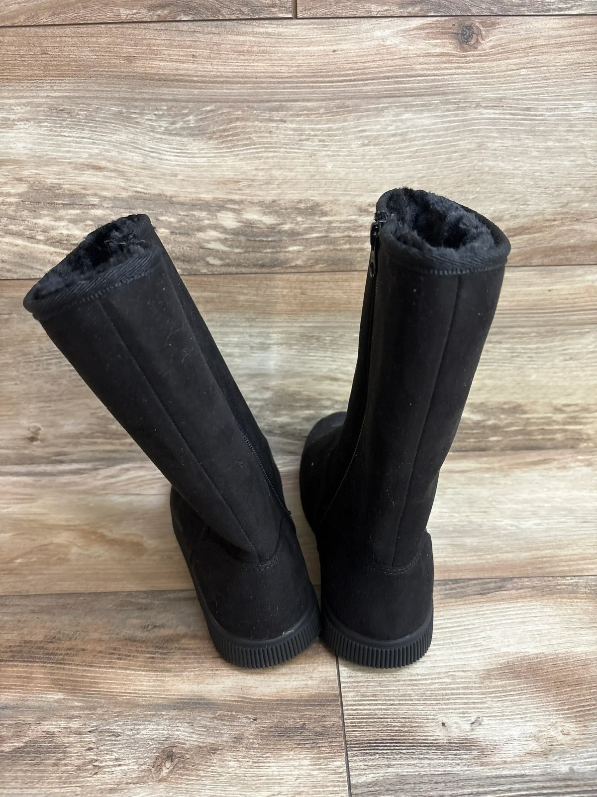 Pair of black children's winter boots with faux fur lining on wood floor