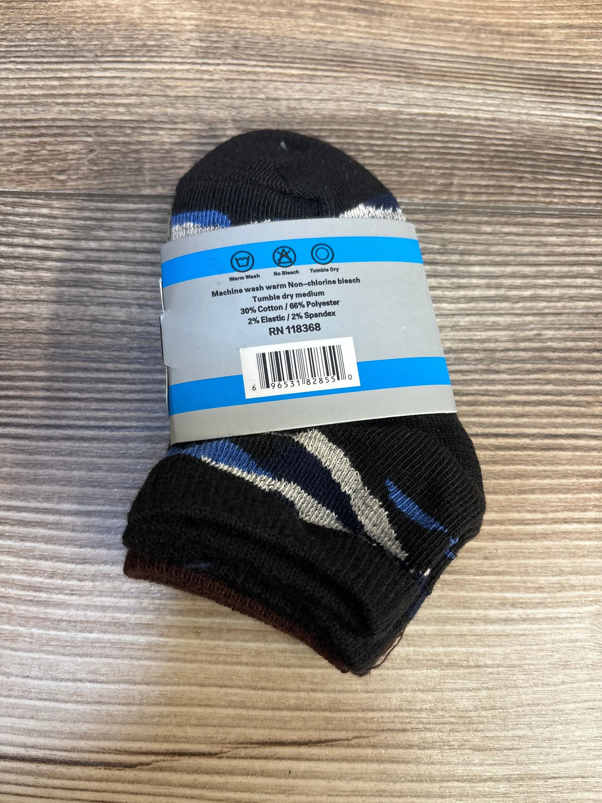 Pack of black and blue striped kids socks with care label, on wood surface