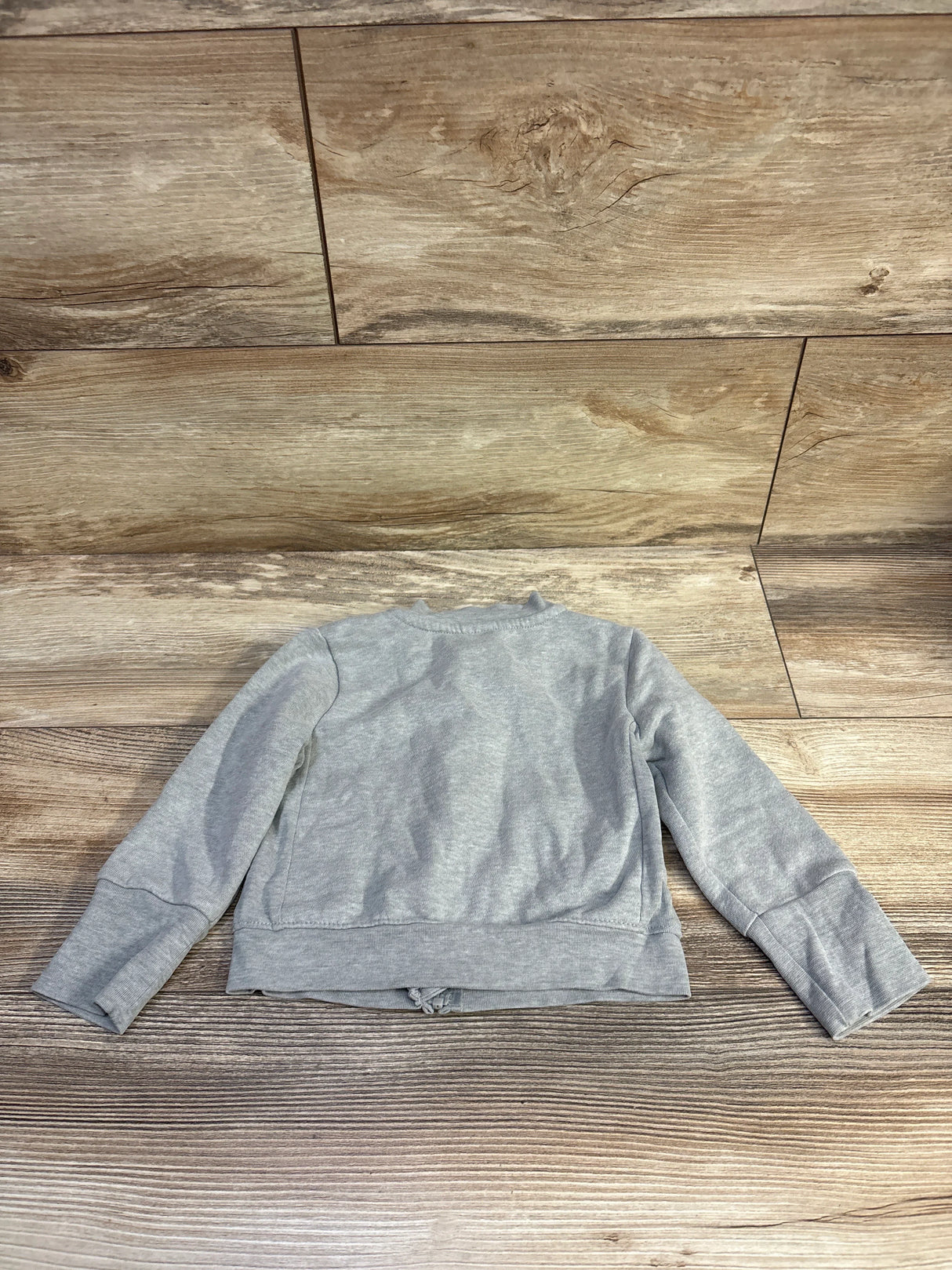 Back view of Hanes zip-up toddler sweatshirt showcasing long sleeves and ribbed cuffs with wood plank background
