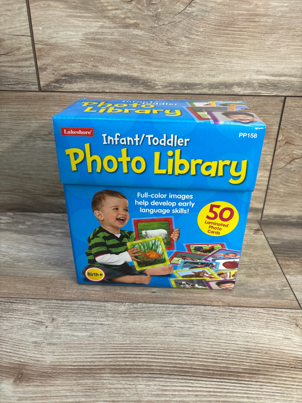 Front view of Lakeshore Infant/Toddler Photo Library showcasing 50 laminated photo cards with a wood floor background