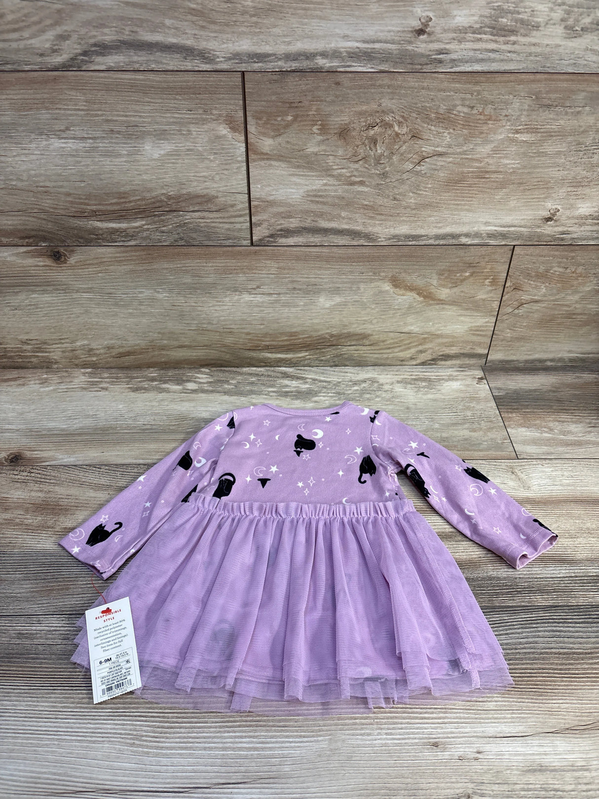 Flat lay of Cat and Jack purple Halloween long-sleeve tulle dress with layered skirt and cat and witch print on wood floor