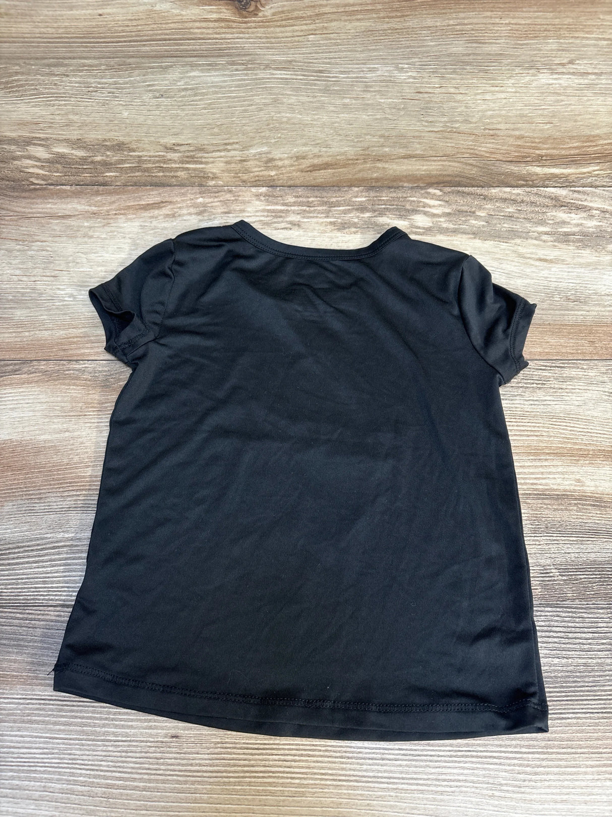 Black kids' short-sleeve t-shirt on wooden surface, ideal for casual wear or resale