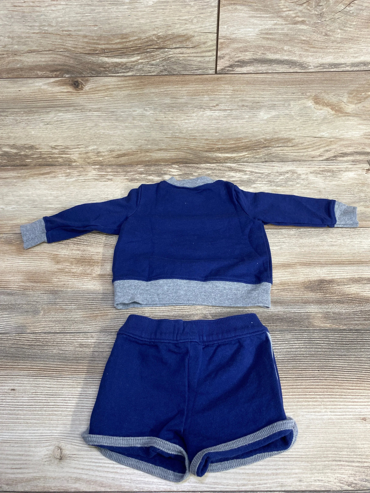 Navy blue and gray long sleeve toddler shirt with matching shorts on wood background