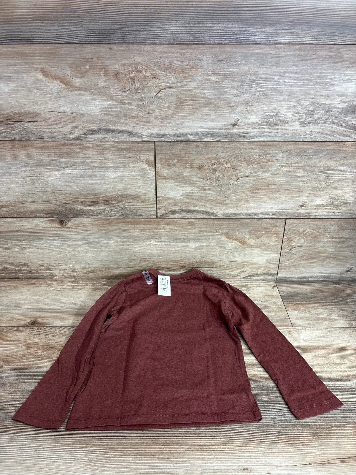 Flat lay of brown Children's Place long-sleeve toddler shirt (5T) showing crew neck and full sleeves on wood backdrop