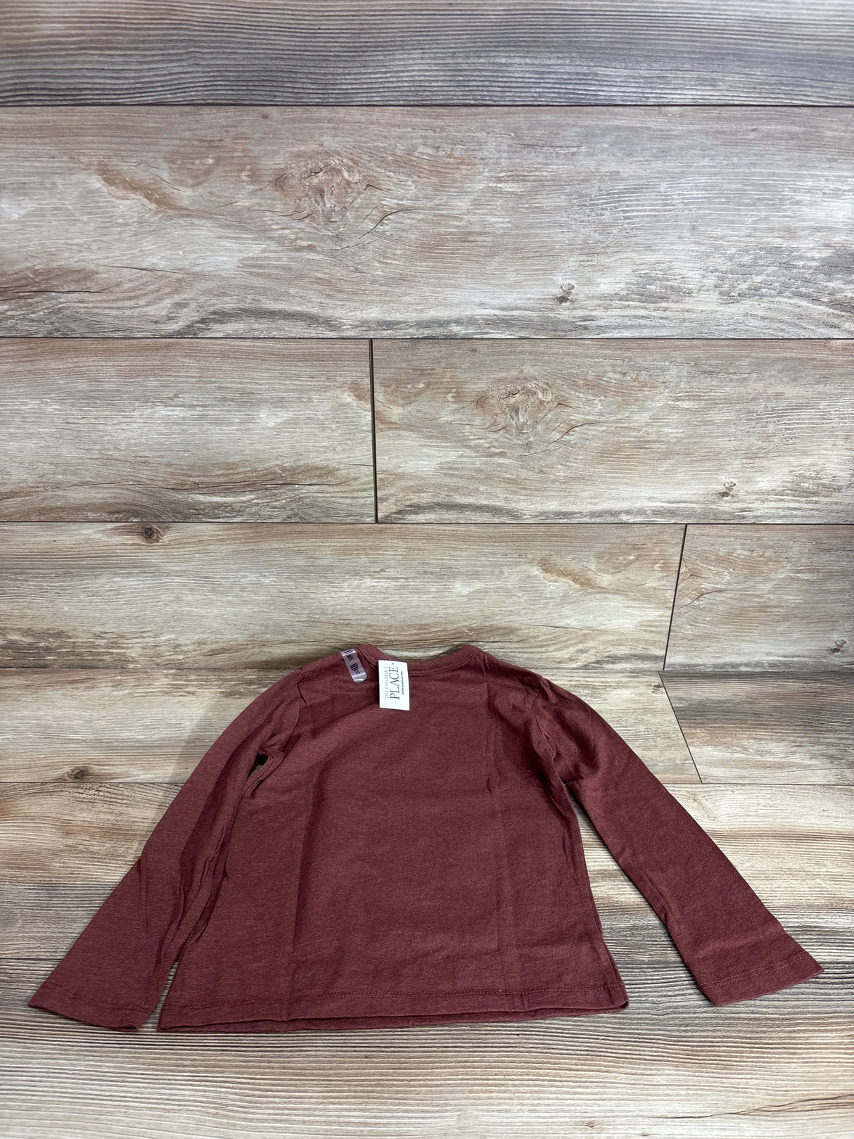 Flat lay of brown Children's Place long-sleeve toddler shirt (5T) showing crew neck and full sleeves on wood backdrop