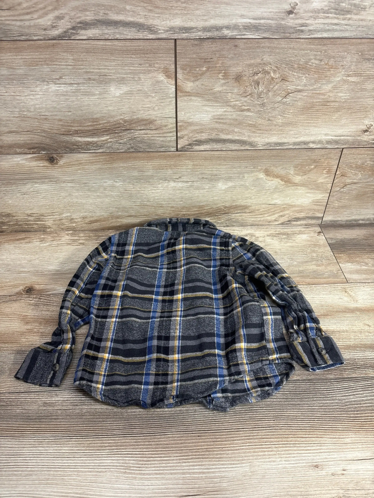Back view of Grey Old Navy 4T plaid flannel button-up shirt showing blue and yellow stripes and long sleeves on wood background