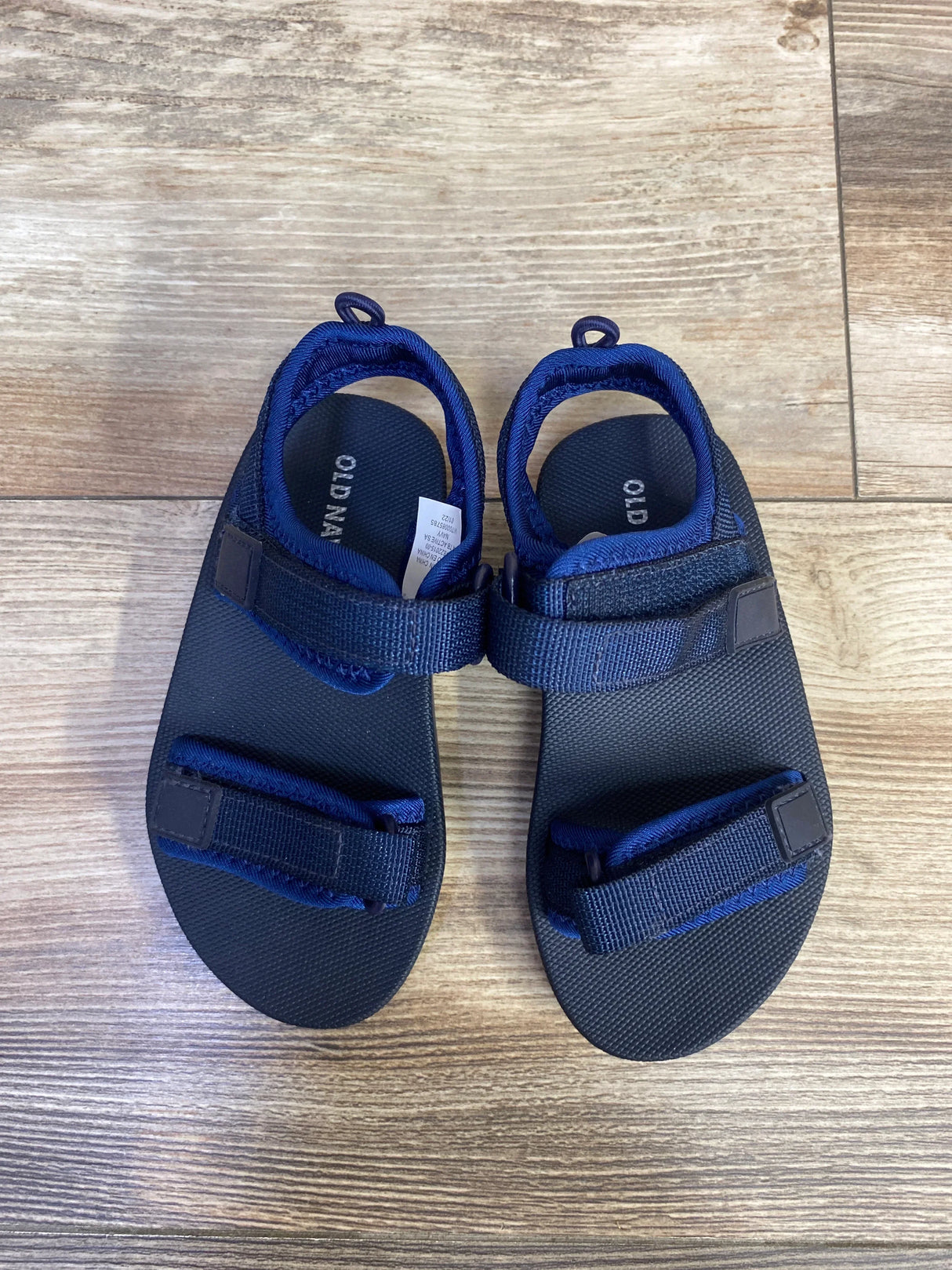 Top view of Old Navy navy toddler double-strap sandals size 8C showing adjustable Velcro straps on wood floor