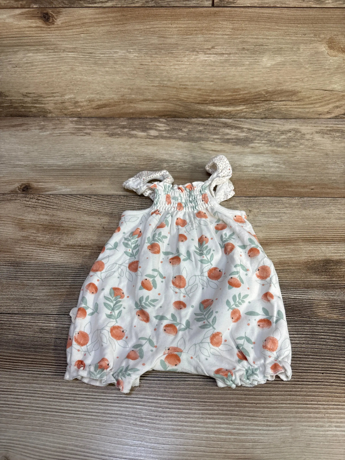 Front view of Rabbit + Bear organic cotton shortie romper with orange fruit and green leaf print on white fabric