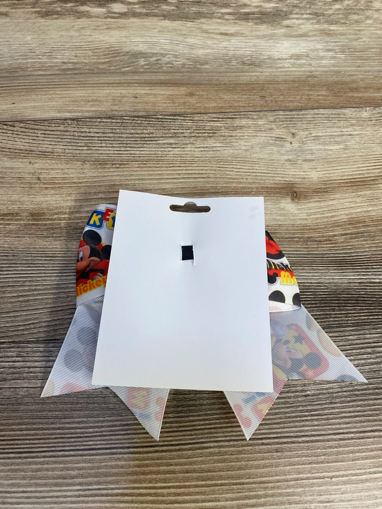 Mickey Mouse theme printed ribbon on wooden surface with blank white tag attached