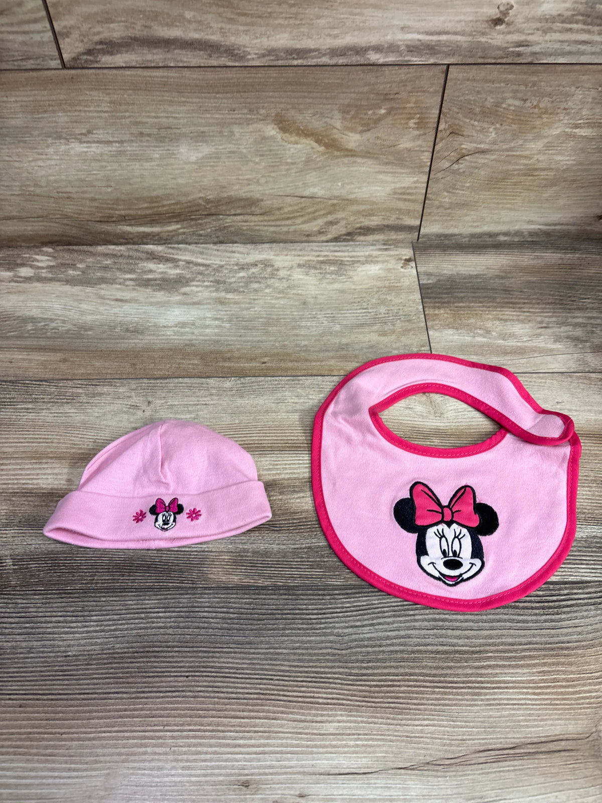 Disney Minnie Mouse pink 2-piece bib and hat set on a wooden background